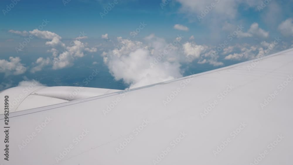 A wing with an airliner engine in flight. Against the backdrop of clouds and blue sky A wing with an airliner engine in flight. Against the backdrop of clouds and blue sky
