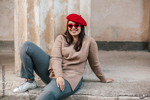 Plus zise model wearing sweater and beret posing on the city street photo