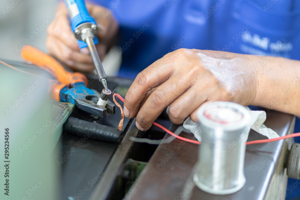 Soldering iron soldering a wire to an electrical component with smoke coming of it lying on top of coloured wires Soldering iron soldering a wire to an electrical component with smoke coming of it lying on top of coloured wires