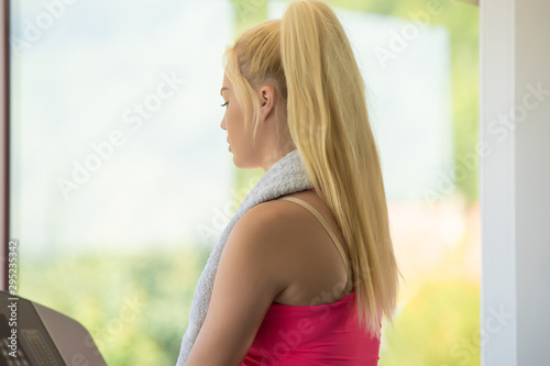 Fit woman on exercise bike wiping sweat with towel at the gym