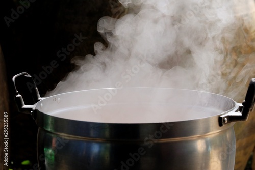 White smoke from a hot cooking pot in kitchen area with dark background 