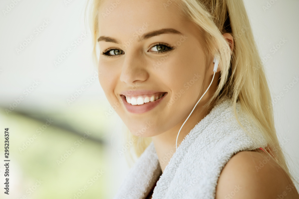Naklejka premium Fit woman on exercise bike wiping sweat with towel at the gym