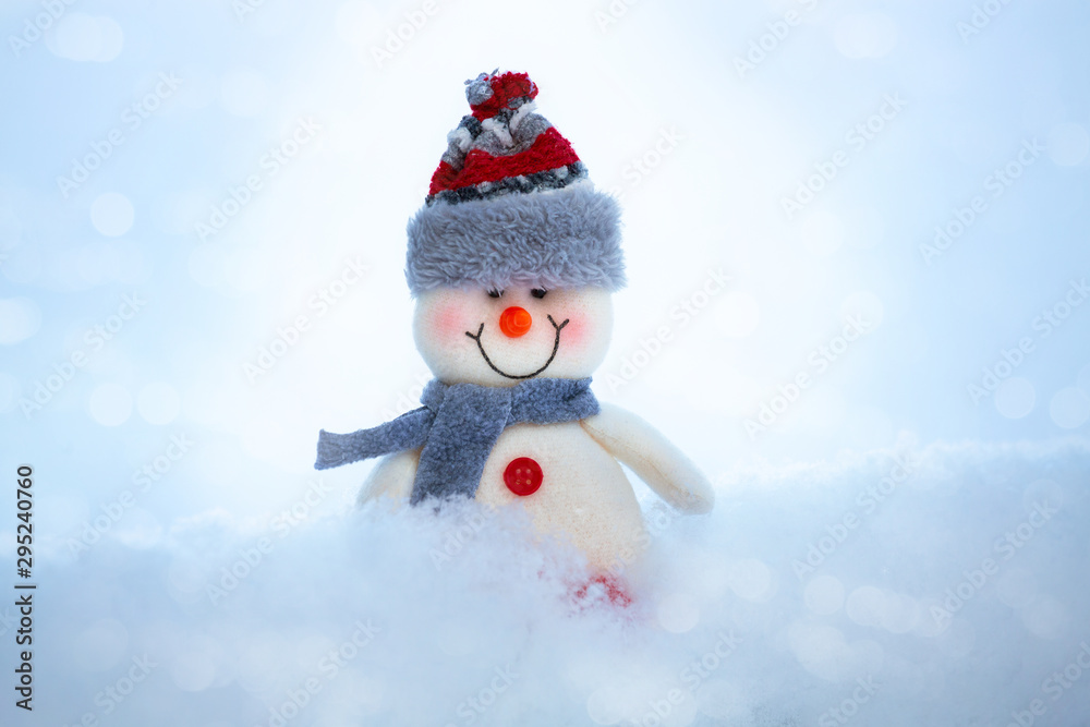On the snow is a happy funny toy snowman. The snowman is wearing a fur hat and scarf. The concept of winter, Christmas, New year. Copy space. horizontal orientation.