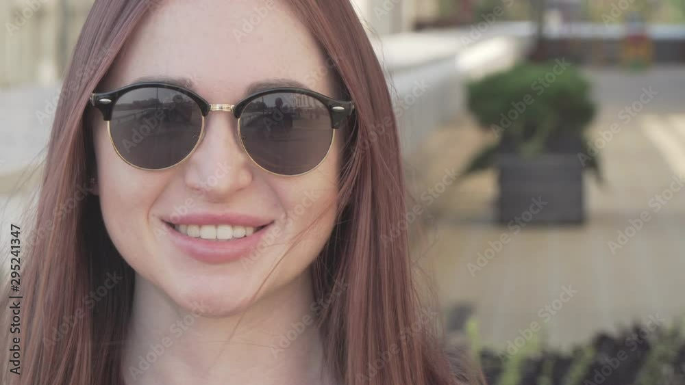 beautiful woman wearing trendy sunglasses smiles happily