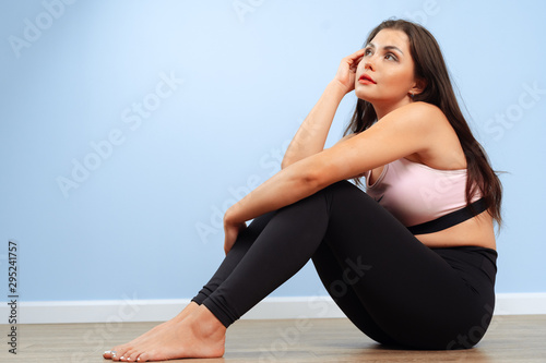Fit woman in sportswear sitting on the floor in a gym