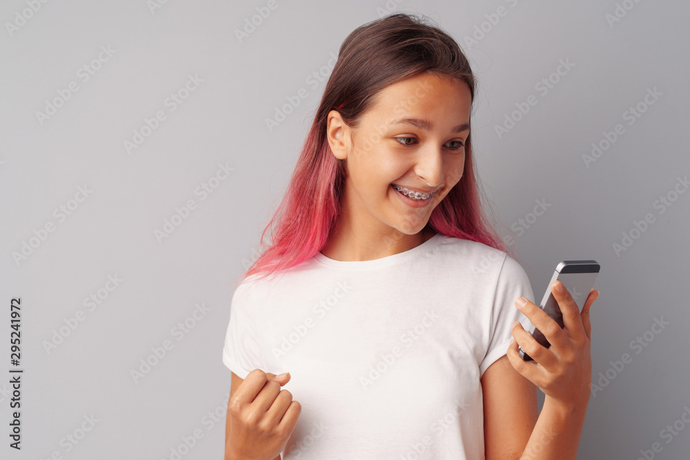 Happy young teen girl winner celebrating success over gray background Happy young teen girl winner celebrating success over gray background