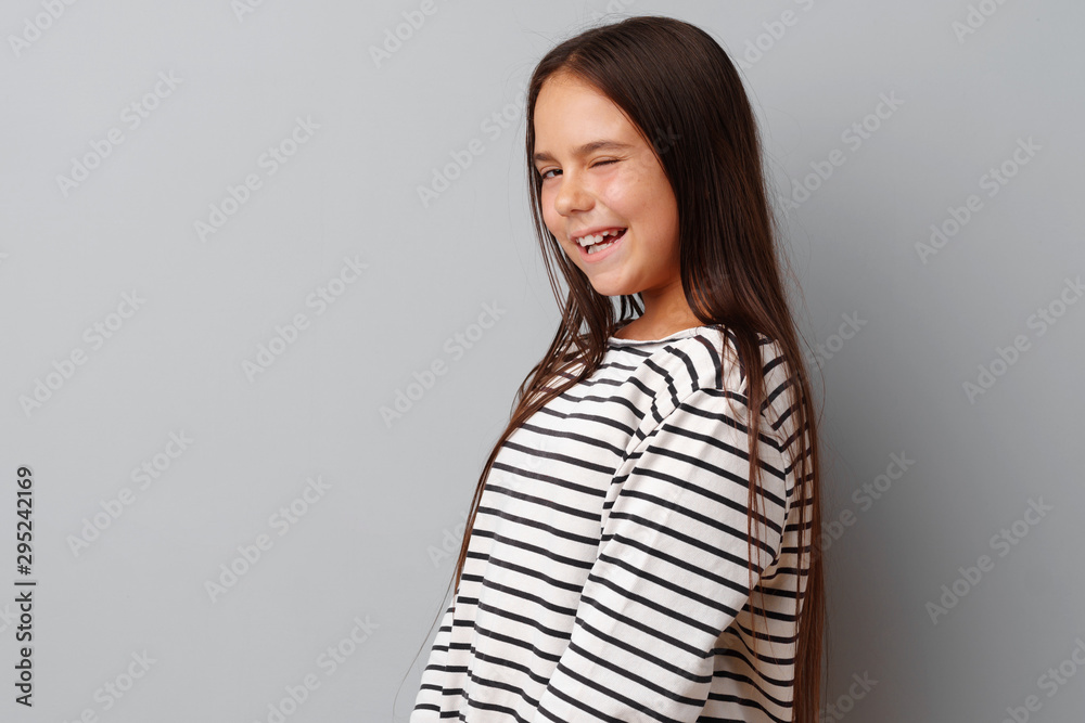 Little girl making a grimace over a grey background Little girl making a grimace over a grey background
