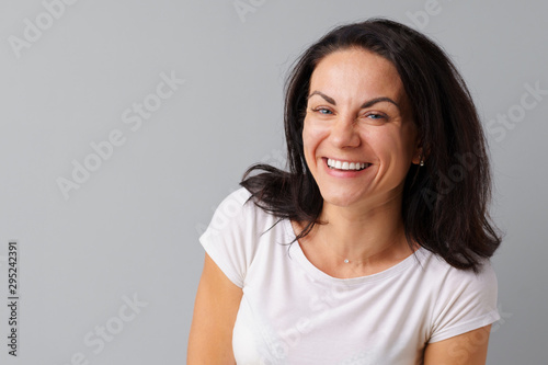 Portrait of joyful brunette young cute woman laughing over a gray background