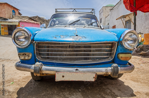 Front part side of an old blue 60's car very used on a dirt road. © JavierBallesterLegua