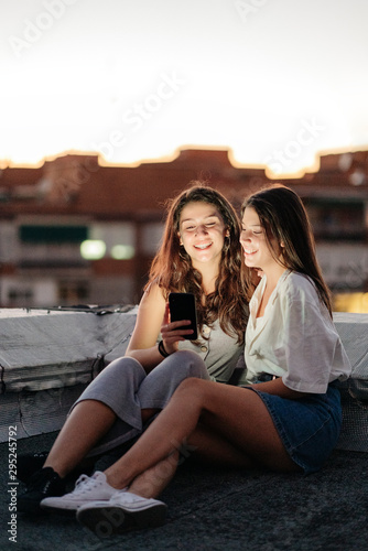 Young female couple using smartphone in a rooftop