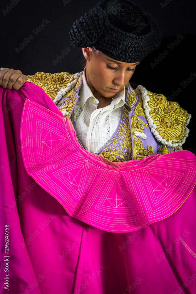 Naklejka premium Woman bullfighter holding capote pink on black background