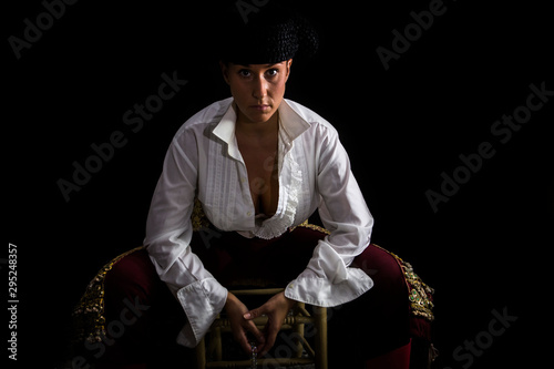 Woman bullfighter sitting on a wooden chair holding a rosary