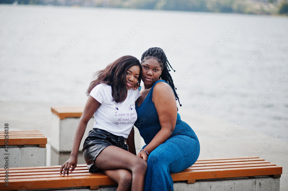 Two african american dark skinned friends female. One of them plus size model, second slim. Having fun and spending time together.