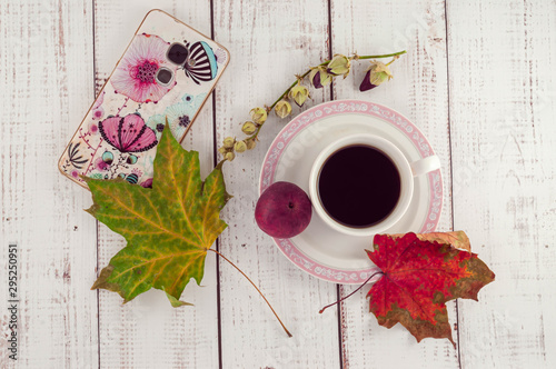 Cup of coffee on a wooden background with autumn maple leaves