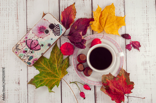 Cup of coffee on a wooden background with autumn maple leaves and chestnuts