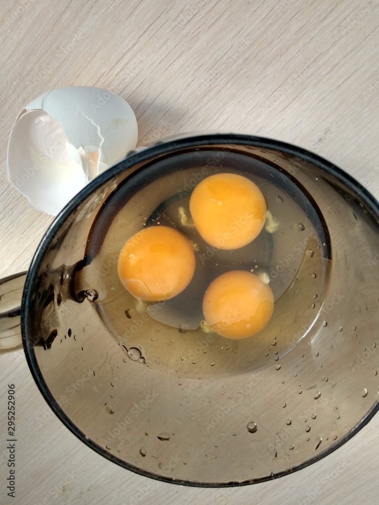 Three raw eggs in a dark glass mug close up Three raw eggs in a dark glass mug close up