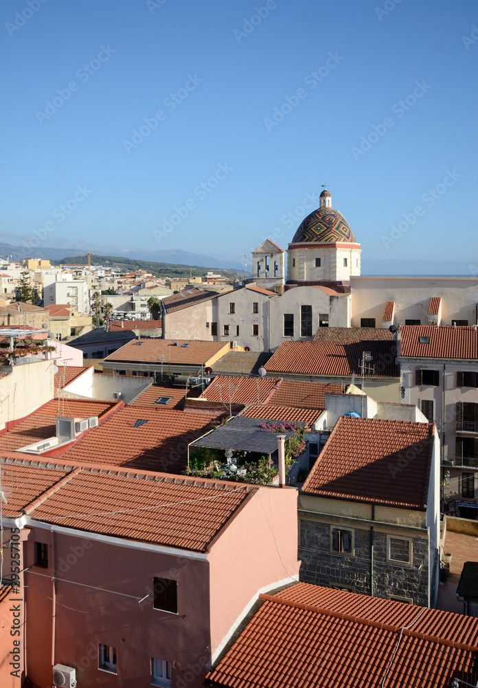Aerial view of the city of Alghero with the red roofs of the houses and the church of San Michele with its colorful majolica dome in evidence