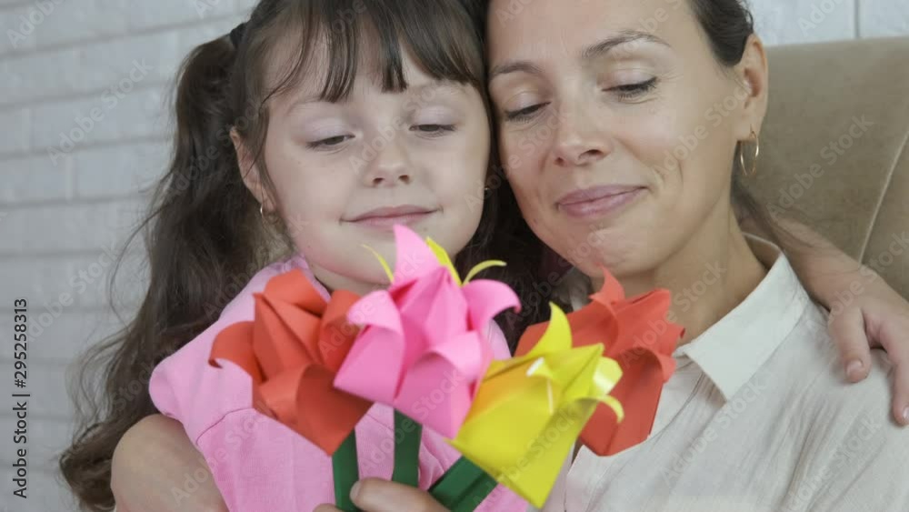 Mothers Day. A child gives mother flowers. Portrait of a mother with a gift of paper flowers from her daughter. Mothers Day. A child gives mother flowers. Portrait of a mother with a gift of paper flowers from her daughter.