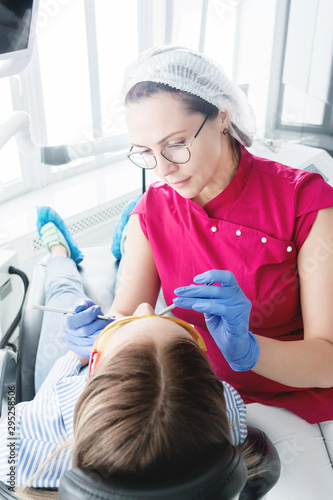 In the dentist s office. A female dentist in glasses is preparing to make a cast of the jaw of a young girl patient. Care clean mouth