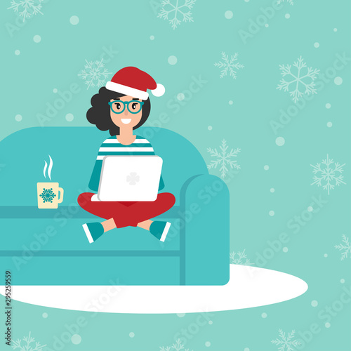 happy freelancer girl with glasses and santa hat on sofa with laptop.