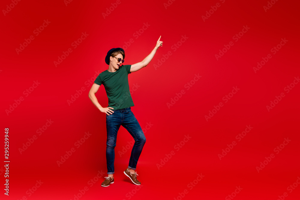 Full size profile side photo of crazy guy have fun on summer weekends celebration aprty dance raise index finger wear denim jeans sneakers outfit isolated over red color background Full size profile side photo of crazy guy have fun on summer weekends celebration aprty dance raise index finger wear denim jeans sneakers outfit isolated over red color background