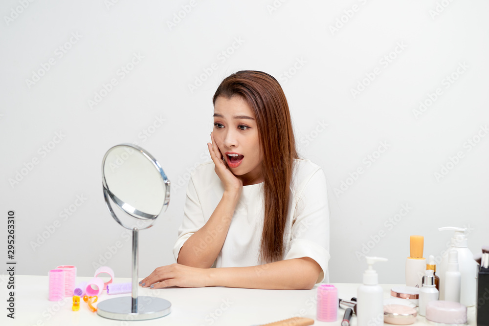 Portrait of brunette woman looking at her face in mirror Portrait of brunette woman looking at her face in mirror