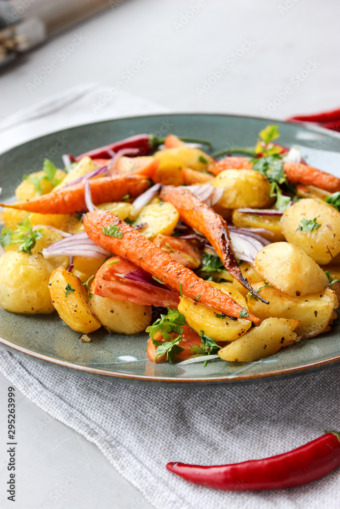 warm salad of baked potatoes and carrots with red onions, spices and tomatoes
