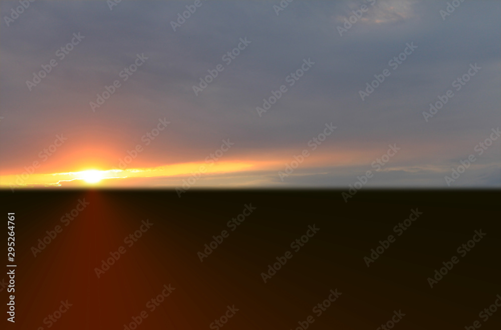 Fototapeta premium Orange sunset in summer over black earth against blue sky
