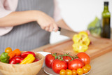 Close-up of woman standing at the table and cutting pepper on cutting board for vegetable salad