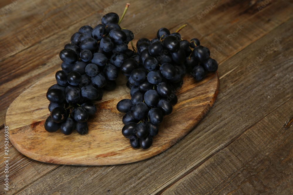 bunch of organic juicy blue-black grapes on a wooden rustic table with copy space for text. bunch of organic juicy blue-black grapes on a wooden rustic table with copy space for text.