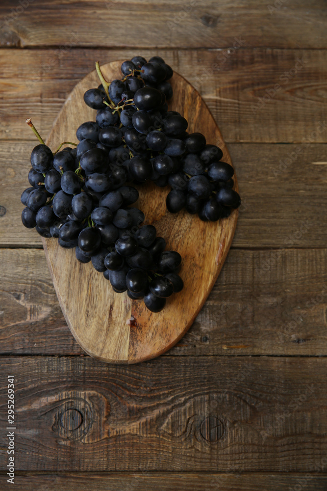 bunch of organic juicy blue-black grapes on a wooden rustic table with copy space for text. Flat lay. Top view. Vertical photo. bunch of organic juicy blue-black grapes on a wooden rustic table with copy space for text. Flat lay. Top view. Vertical photo.
