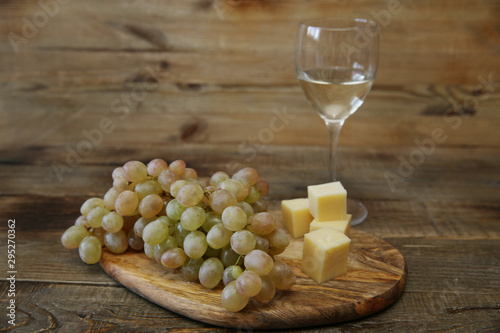 organic white grapes and white wine and cheese on the wooden rustic table with copy space for text.