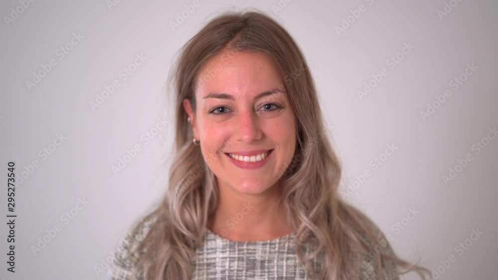 Close up footage portrait of beautiful blonde caucasian woman smiling and laughing at the camera isolated on neutral background. In facial expression and happiness concept.