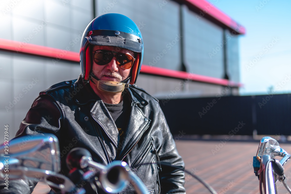 Portrait of a middle-aged man, an old biker in a leather jacket on a retro