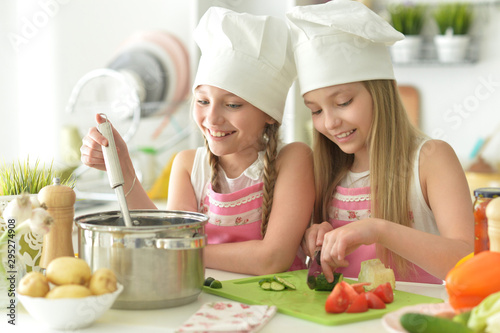 Portrait of girls preparing delicious fresh salad in kitchen