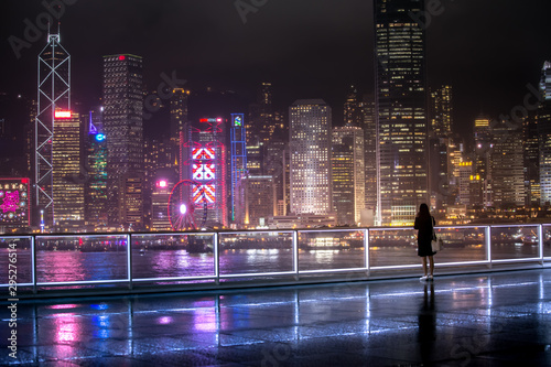 People stand in front of Victoria Harbor, Hong Kong at raining night