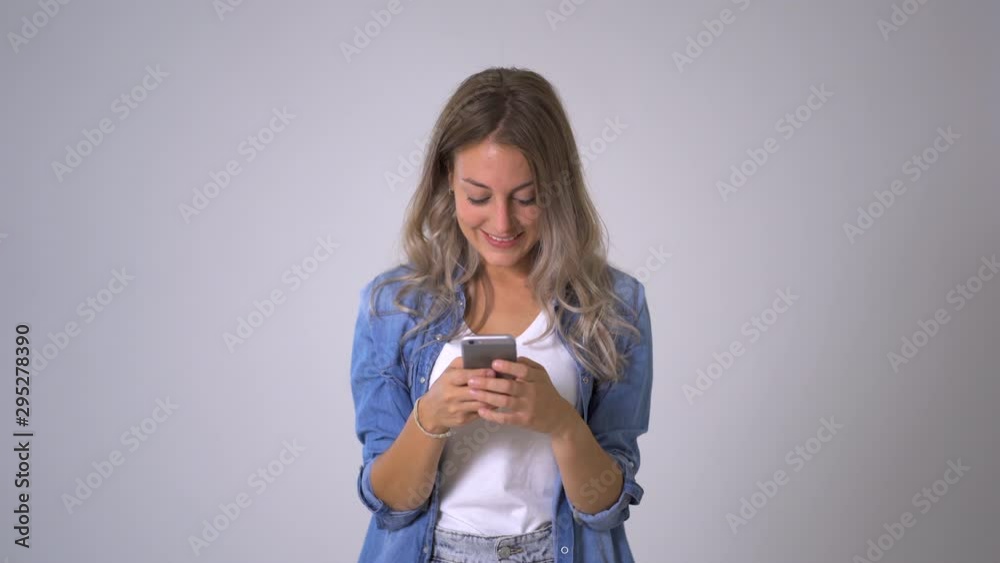 Beautiful blonde woman using smart phone posting on her blog in social media and happy with likes from followers and online business.Isolated on neutral background. In entrepreneur, online networking Beautiful blonde woman using smart phone posting on her blog in social media and happy with likes from followers and online business.Isolated on neutral background. In entrepreneur, online networking