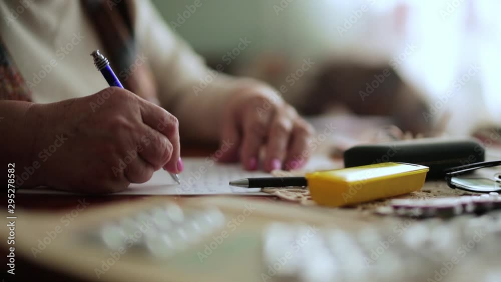 Grandma handwriting a letter to her family. Tablets for her medical condition Grandma handwriting a letter to her family. Tablets for her medical condition