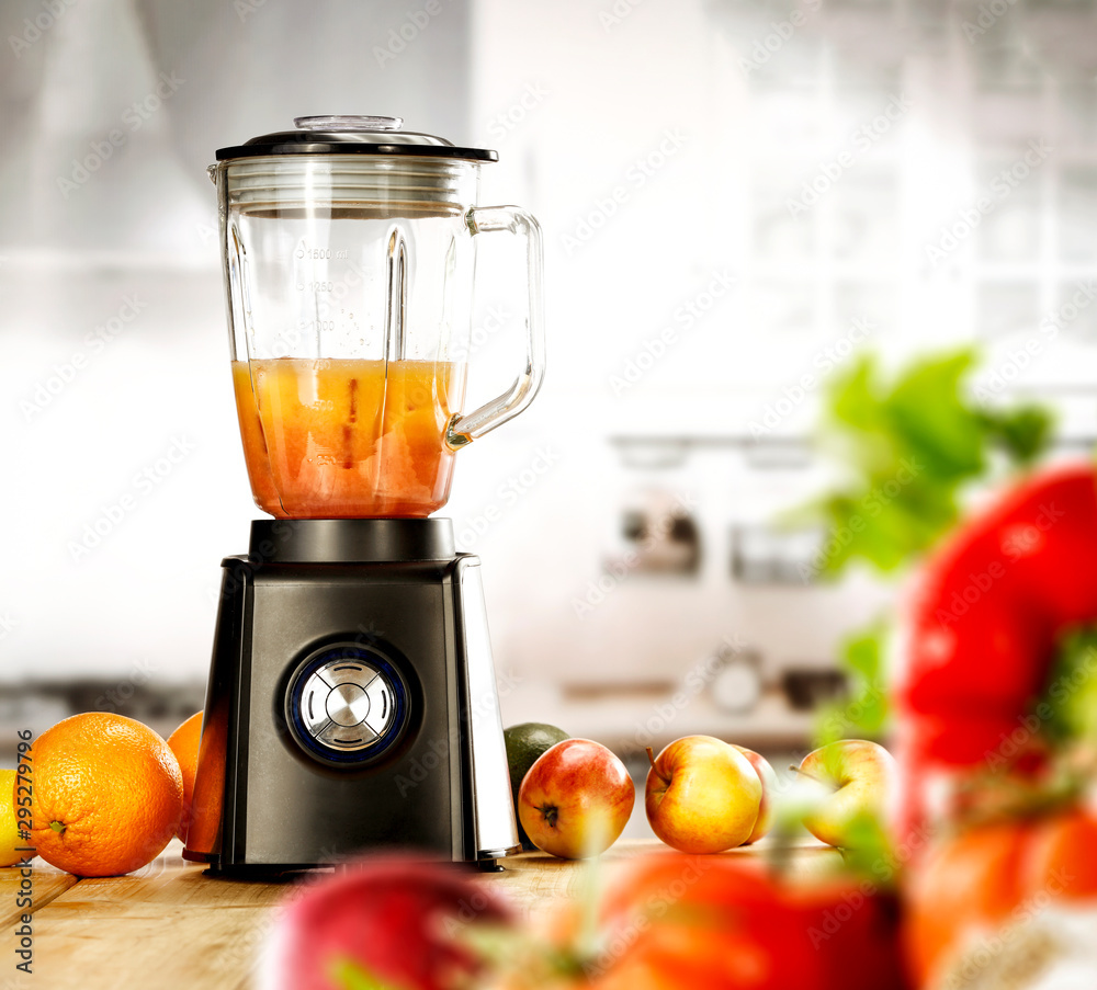 A blender on the table with some fruit and vegetables with blurred kitchen background. A blender on the table with some fruit and vegetables with blurred kitchen background.