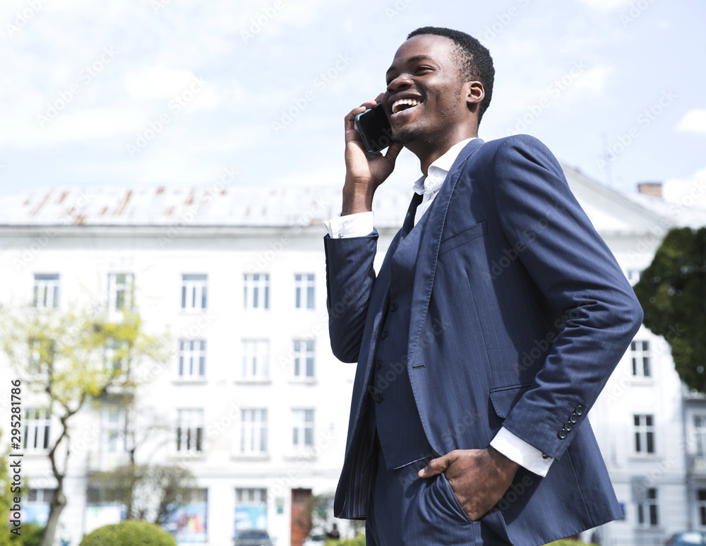 Successful young businessman with hands in his pocket talking on mobile phone Successful young businessman with hands in his pocket talking on mobile phone
