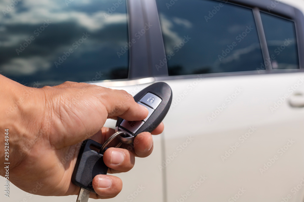 Hand man hold button unlock on the car remote control for unlock door white car. Hand man hold button unlock on the car remote control for unlock door white car.