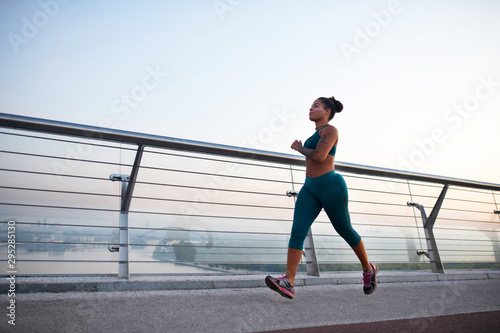 Dark-skinned woman wearing leggings enjoying morning run