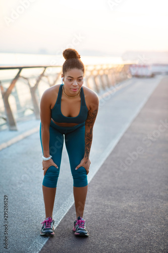 Dark-skinned woman wearing leggings feeling exhausted after run