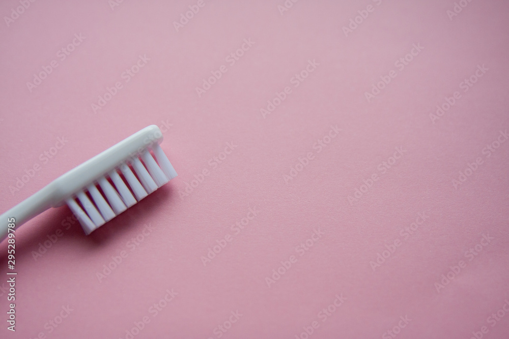 White toothbrush used for cleaning the teeth on pink background White toothbrush used for cleaning the teeth on pink background