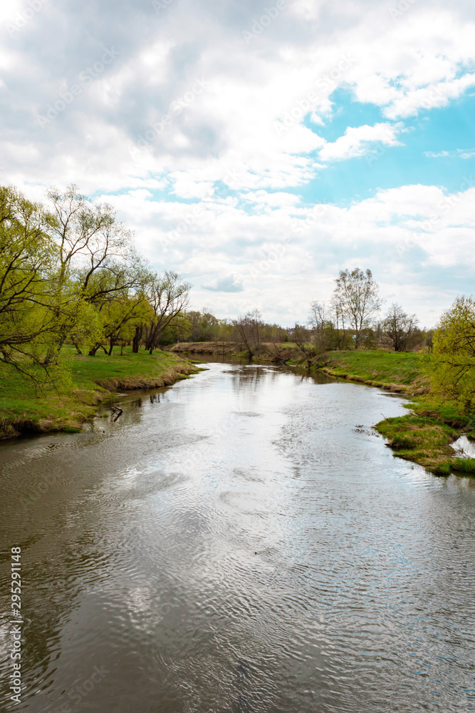 Landscape view on river shore, bushes, trees and village houses. Blue sky and clouds background Landscape view on river shore, bushes, trees and village houses. Blue sky and clouds background