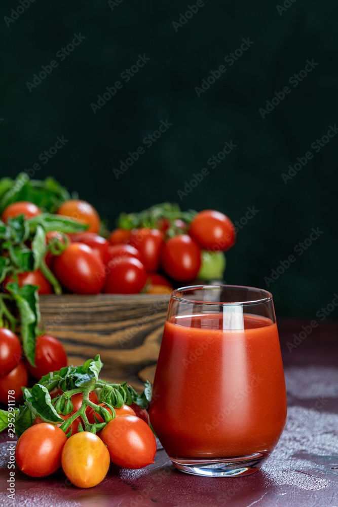 Glass of fresh delicious jummy red tomato juice and fresh tomatoes in wooden box. Dark background. Close up. Gmo free. Natural good food Glass of fresh delicious jummy red tomato juice and fresh tomatoes in wooden box. Dark background. Close up. Gmo free. Natural good food