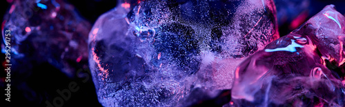 panoramic shot of transparent ice cubes with purple colorful lighting isolated on black photo