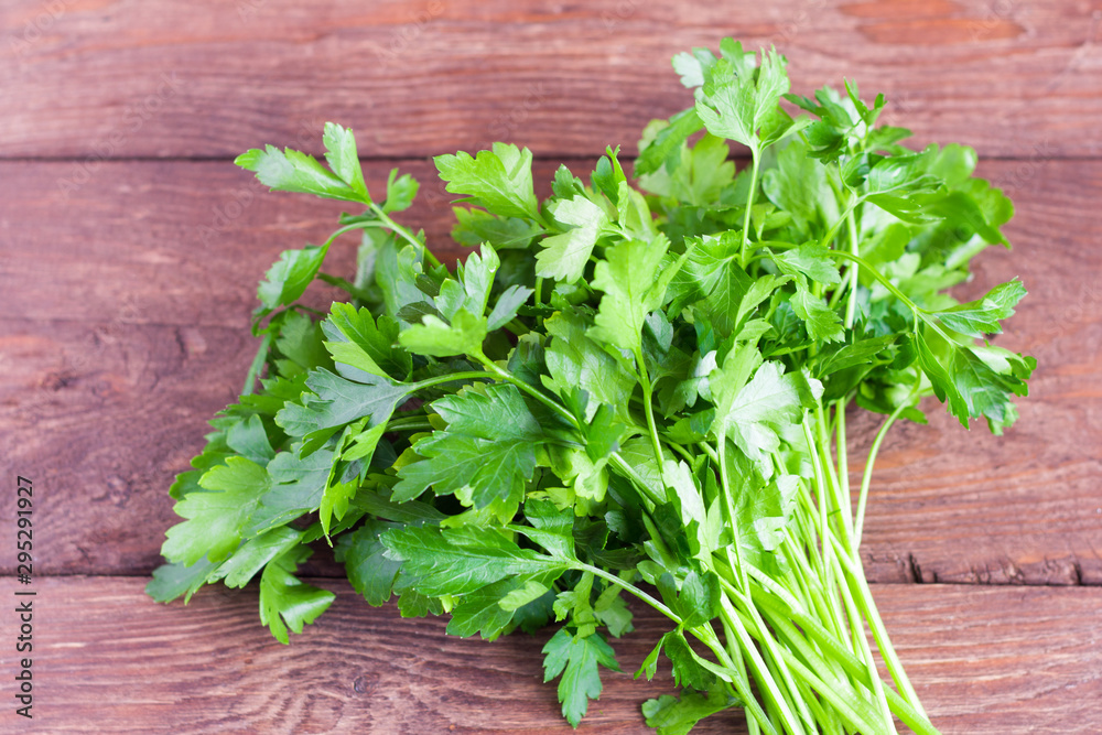 Bunch of fresh parsley on the background of a wooden table. Fresh parsley on a wooden background. Parsley closeup on a village Board Bunch of fresh parsley on the background of a wooden table. Fresh parsley on a wooden background. Parsley closeup on a village Board