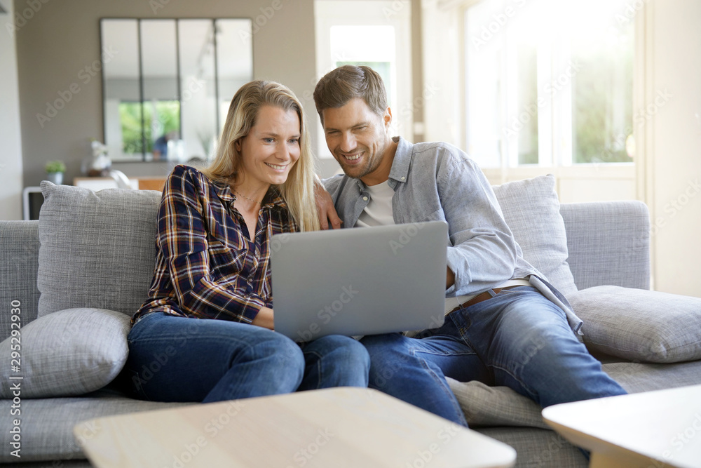 Cheerful couple at home using laptop Cheerful couple at home using laptop