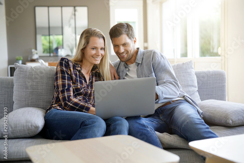 Cheerful couple at home using laptop